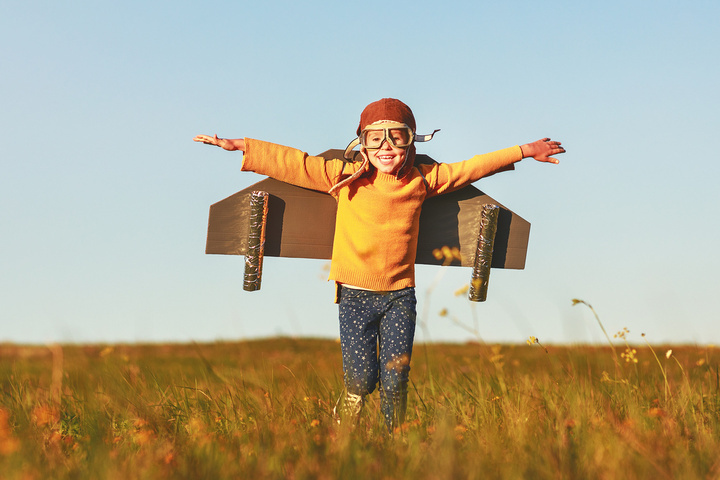 Child pilot aviator with wings of airplane dreams of traveling in summer in nature at sunset
