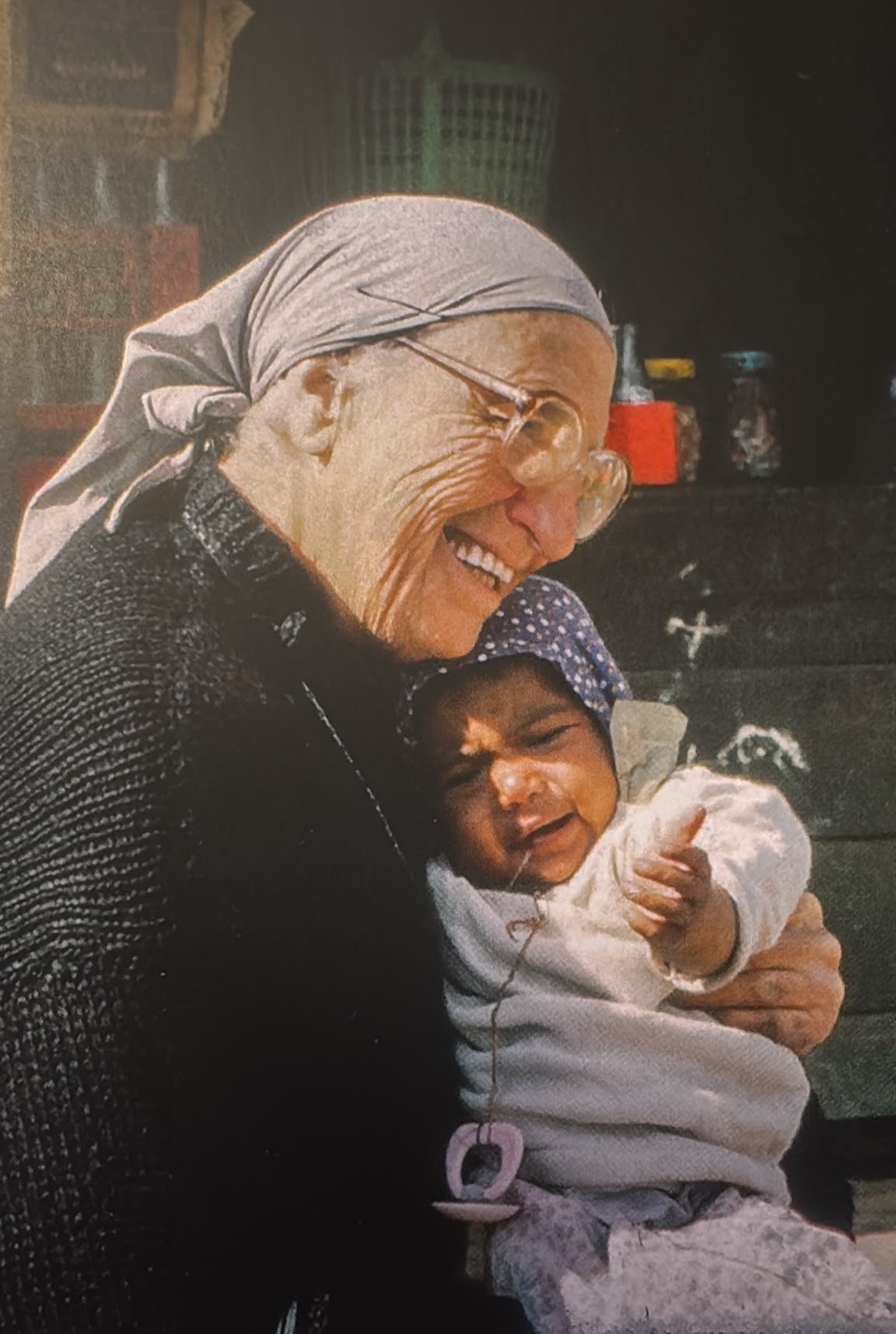 Caritas Homepage - Waltraud Ältere Ordensfrau hält ein Kleinkind auf dem Arm.